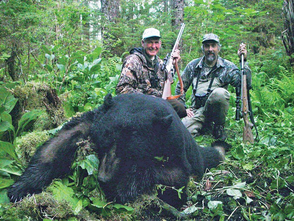 two men with a black bear