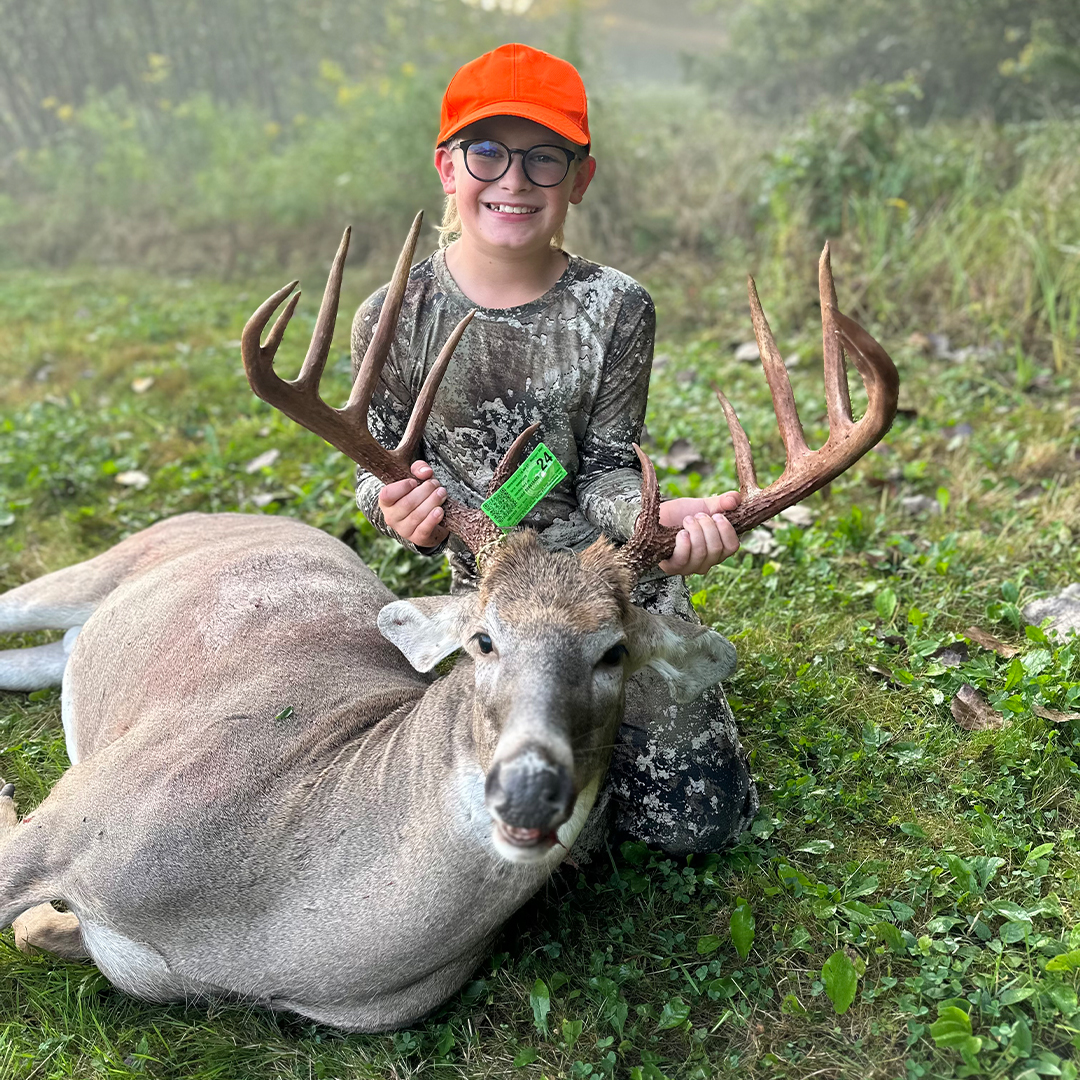 young hunter with harvested whitetail buck